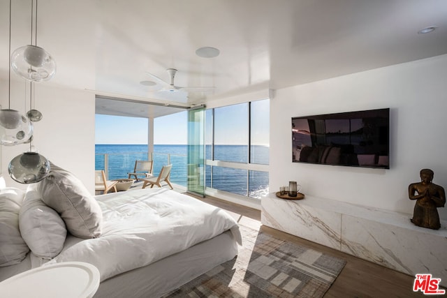 bedroom with ceiling fan, expansive windows, and hardwood / wood-style floors