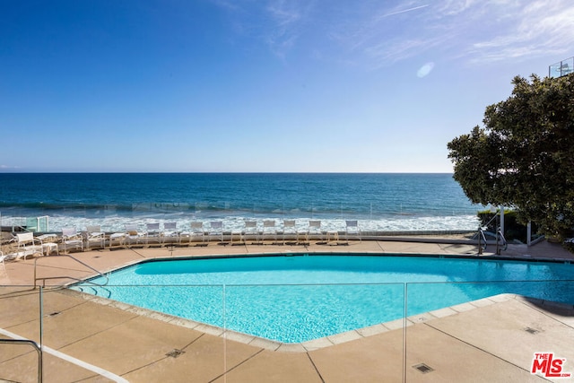 view of pool featuring a water view and a view of the beach