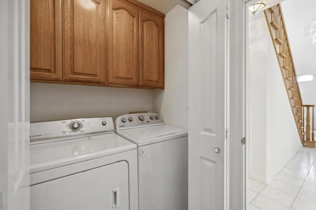 laundry room with washer and dryer, light tile patterned floors, and cabinets