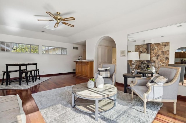 living room featuring dark hardwood / wood-style floors, ceiling fan, and a wood stove