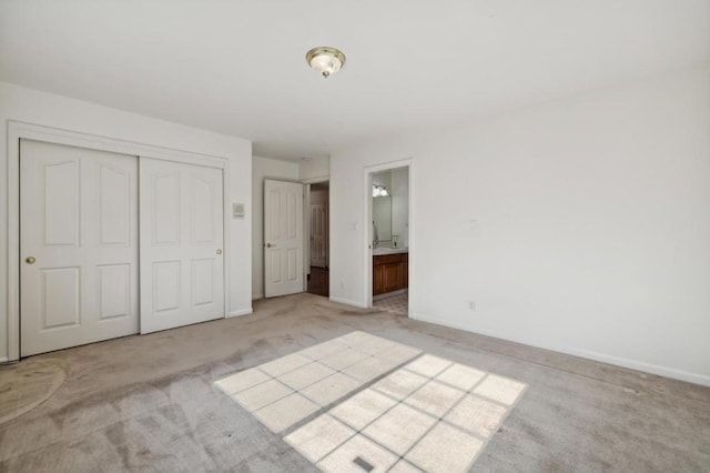 unfurnished bedroom featuring connected bathroom, light colored carpet, and a closet