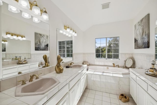 bathroom with lofted ceiling, tiled bath, tile patterned flooring, and vanity