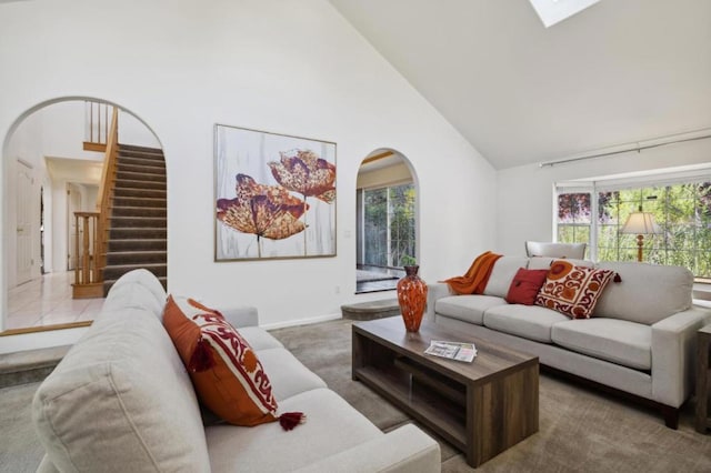 living room with carpet floors, a skylight, and high vaulted ceiling