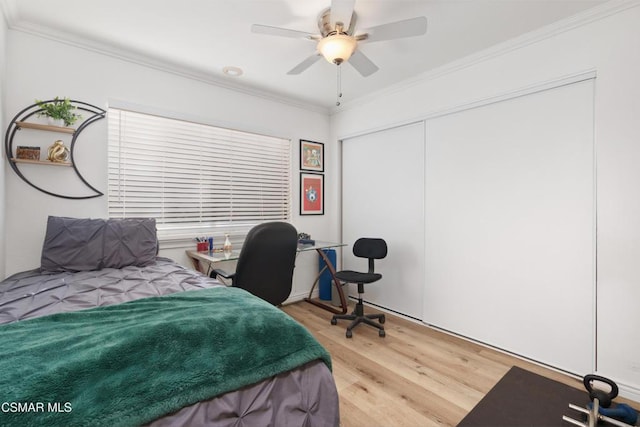 bedroom featuring ceiling fan, a closet, crown molding, and light hardwood / wood-style floors