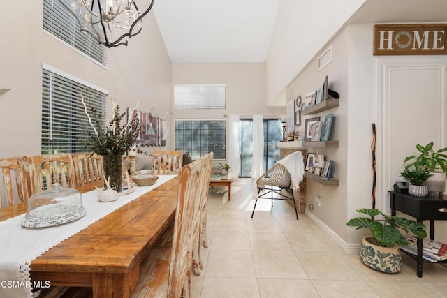 tiled dining room with a high ceiling, plenty of natural light, and an inviting chandelier