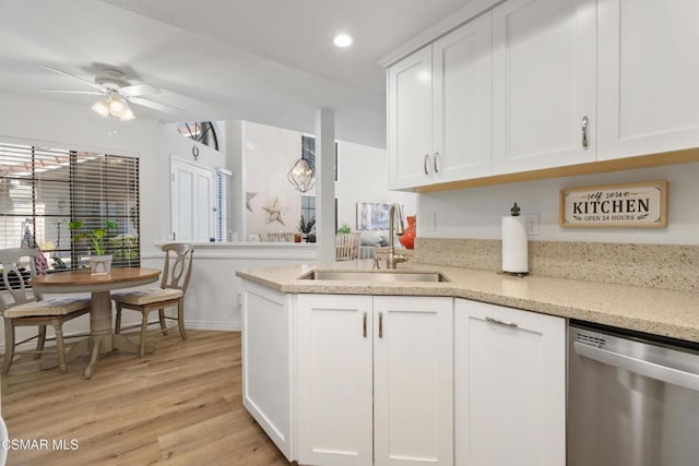 kitchen featuring white cabinets, stainless steel dishwasher, light hardwood / wood-style flooring, light stone counters, and sink