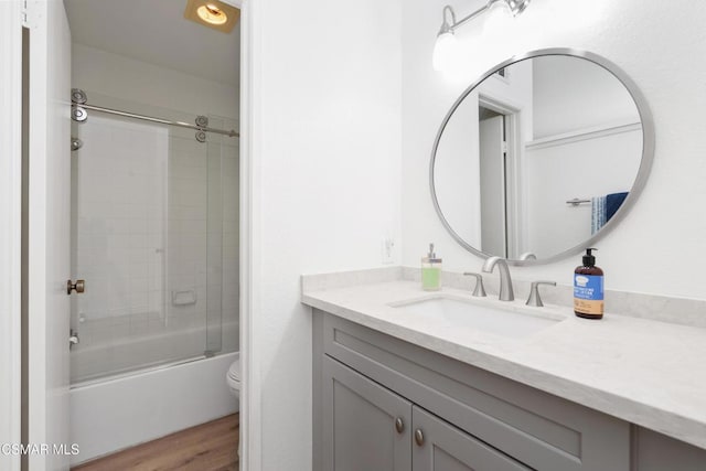 full bathroom featuring combined bath / shower with glass door, vanity, toilet, and hardwood / wood-style floors