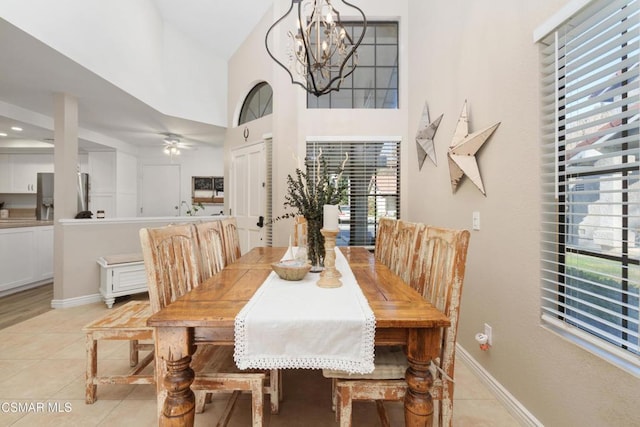 tiled dining area featuring a towering ceiling and ceiling fan with notable chandelier