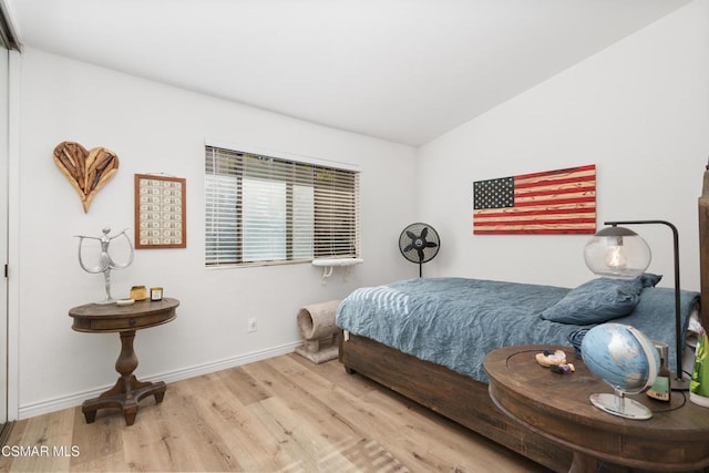 bedroom with light wood-type flooring and vaulted ceiling