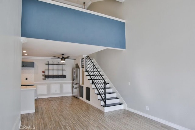 staircase with ceiling fan, crown molding, and hardwood / wood-style flooring