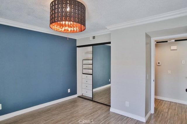 unfurnished bedroom featuring a textured ceiling, crown molding, and wood-type flooring