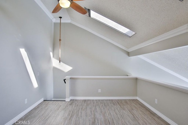 bonus room with a textured ceiling, ceiling fan, vaulted ceiling with skylight, and hardwood / wood-style floors