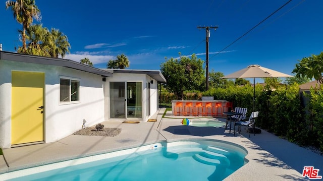 view of swimming pool featuring a patio area and exterior bar