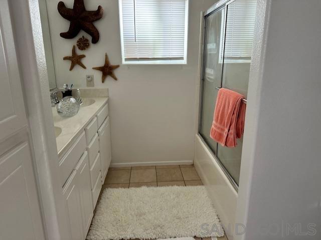 bathroom with bath / shower combo with glass door, tile patterned floors, and vanity