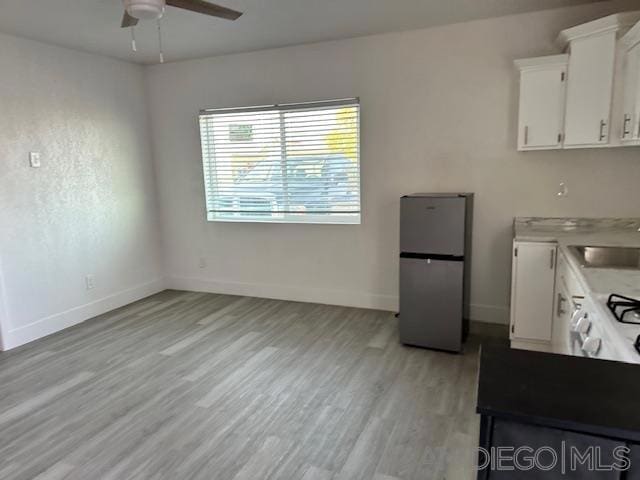 kitchen featuring light hardwood / wood-style floors, ceiling fan, stainless steel refrigerator, white cabinets, and sink