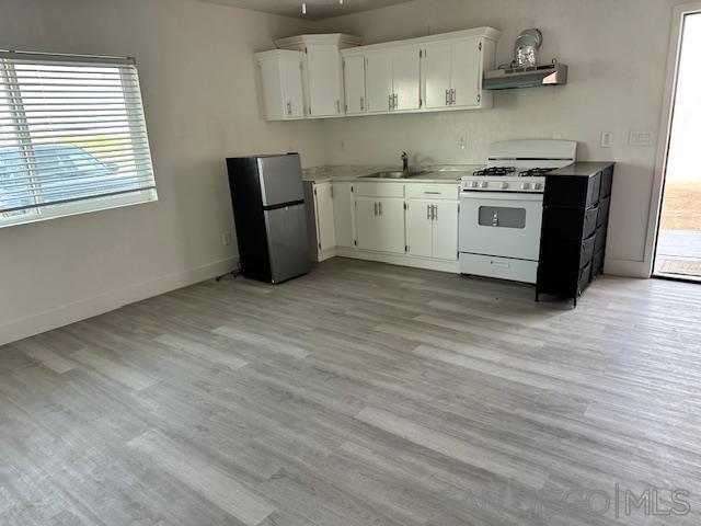 kitchen with sink, stainless steel refrigerator, white cabinetry, light wood-type flooring, and white range with gas stovetop