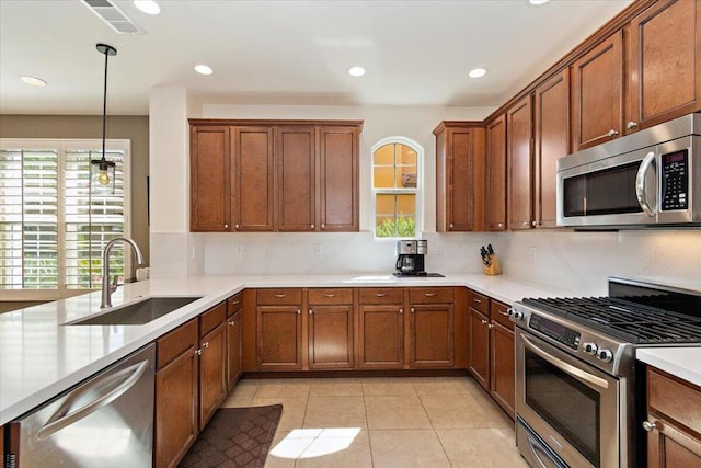 kitchen with appliances with stainless steel finishes, decorative light fixtures, tasteful backsplash, sink, and light tile patterned floors