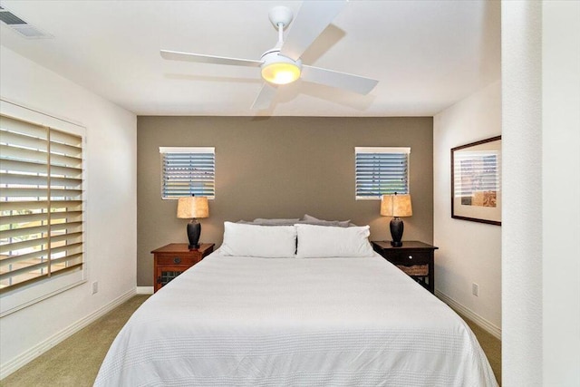 bedroom with ceiling fan, multiple windows, and light carpet