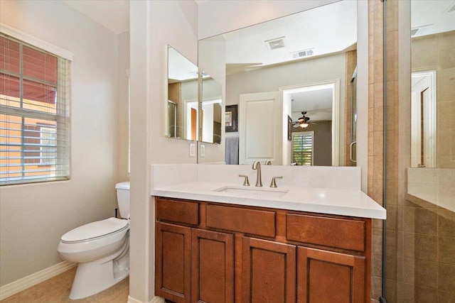 bathroom with a shower with shower door, tile patterned floors, vanity, toilet, and ceiling fan