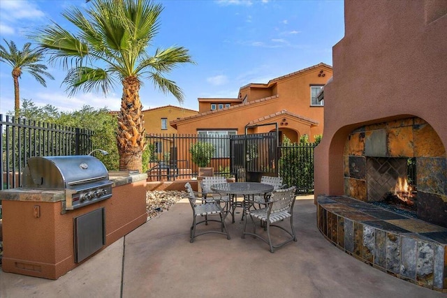 view of patio / terrace with grilling area and an outdoor stone fireplace