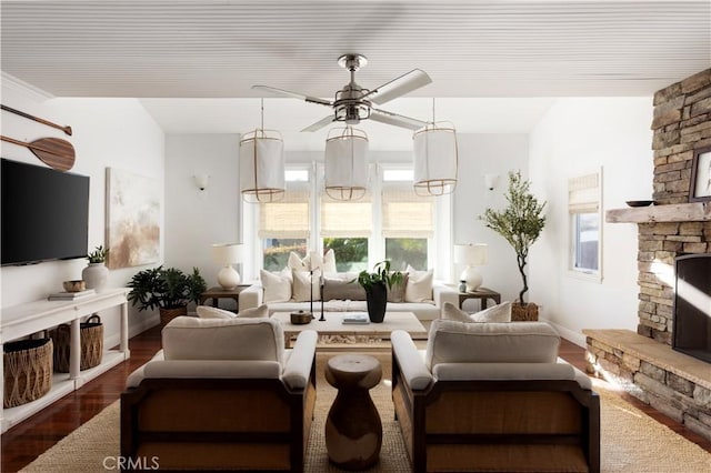 living room with ceiling fan, dark hardwood / wood-style flooring, and a stone fireplace