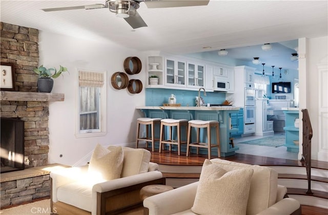 living room featuring ceiling fan, a fireplace, and sink