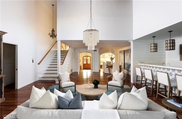 living room with dark wood-type flooring, a high ceiling, and an inviting chandelier