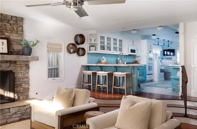 living room with ceiling fan, a fireplace, and sink