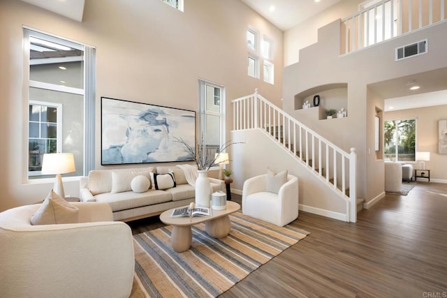 living room featuring dark hardwood / wood-style flooring and a towering ceiling