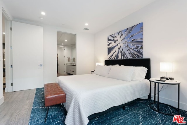 bedroom featuring connected bathroom and hardwood / wood-style flooring