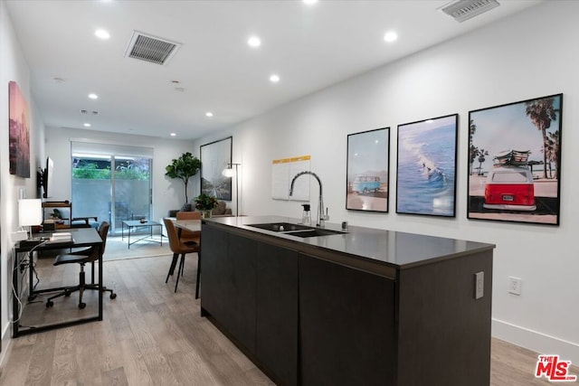 kitchen with a kitchen island with sink, light hardwood / wood-style flooring, and sink