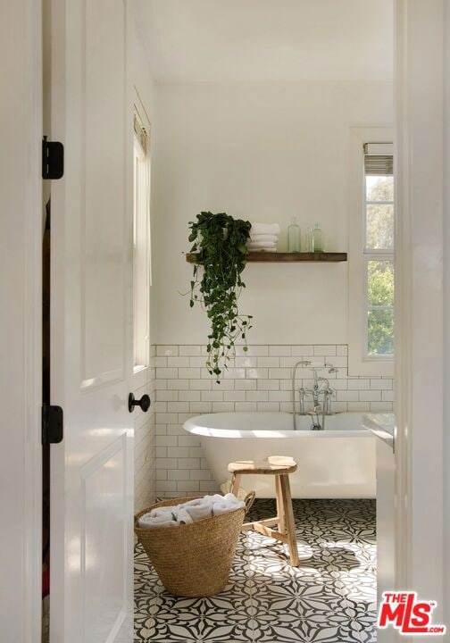 bathroom featuring tile patterned flooring, tile walls, and a tub to relax in