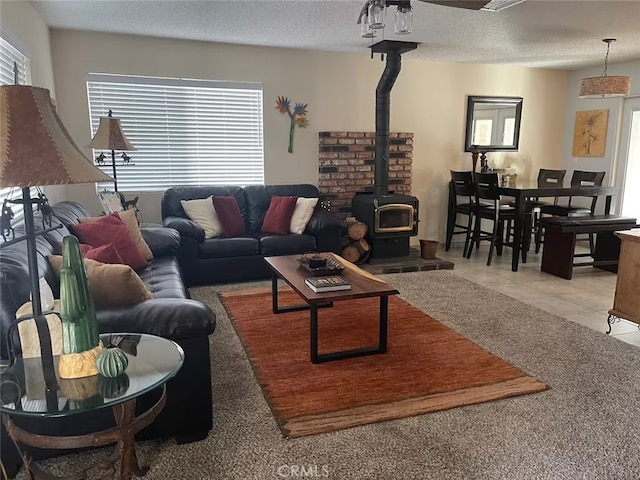 living room with plenty of natural light, light tile patterned flooring, a wood stove, and a textured ceiling