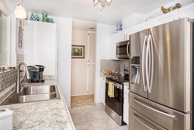 kitchen with stainless steel appliances, white cabinets, backsplash, and sink