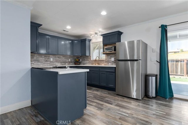 kitchen featuring sink, ornamental molding, dark hardwood / wood-style flooring, stainless steel appliances, and backsplash