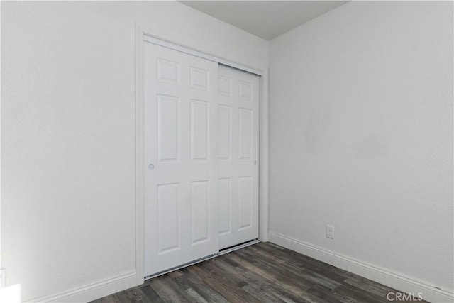 unfurnished bedroom with a closet and dark hardwood / wood-style floors