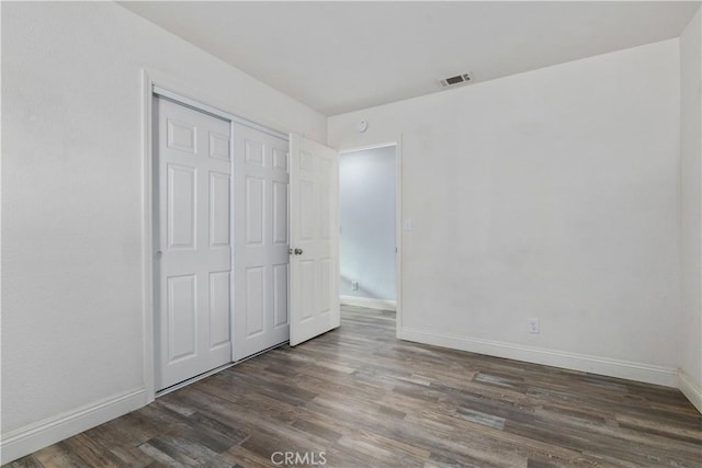 unfurnished bedroom with dark hardwood / wood-style floors and a closet