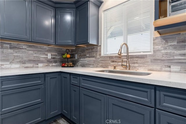 kitchen featuring sink, backsplash, and blue cabinets