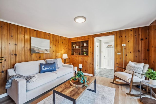 living room featuring ornamental molding, built in features, and light hardwood / wood-style floors