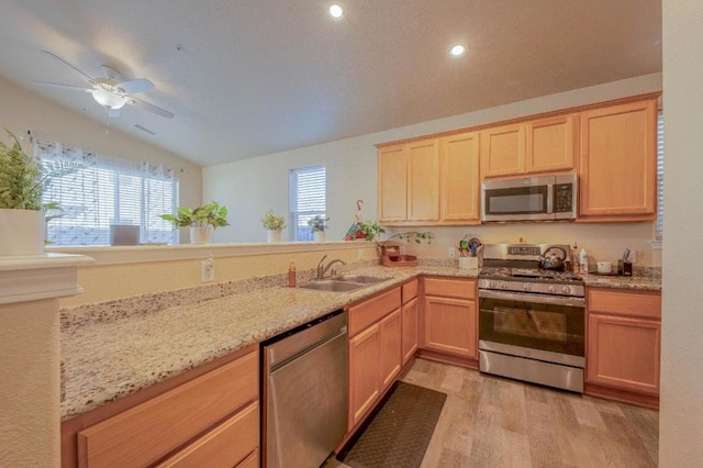 kitchen featuring lofted ceiling, sink, light brown cabinets, light wood-type flooring, and appliances with stainless steel finishes