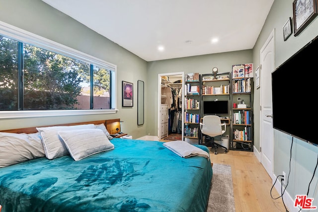 bedroom featuring a closet, a walk in closet, and light hardwood / wood-style flooring