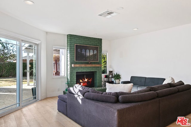 living room featuring a brick fireplace and light hardwood / wood-style floors