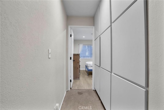 hallway featuring light colored carpet