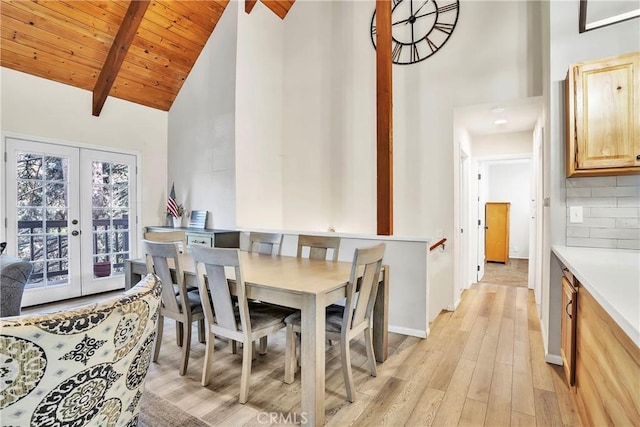 dining room featuring wood ceiling, light wood-type flooring, french doors, high vaulted ceiling, and beamed ceiling