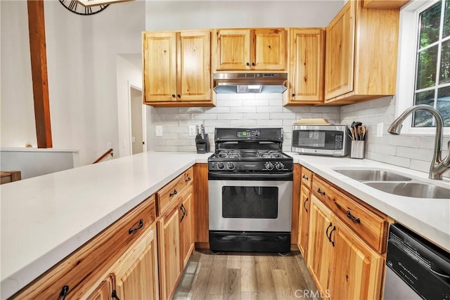 kitchen featuring sink, backsplash, appliances with stainless steel finishes, and light hardwood / wood-style flooring