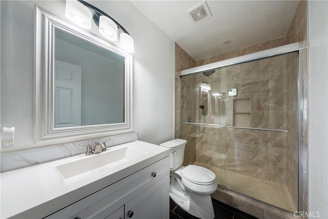 bathroom featuring toilet, vanity, and a shower with shower door