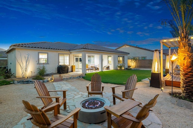 patio terrace at dusk featuring a fire pit and grilling area