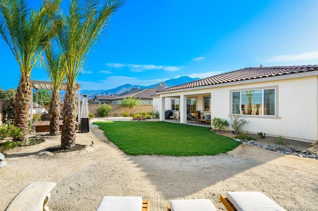 back of property with a mountain view, a yard, and a patio