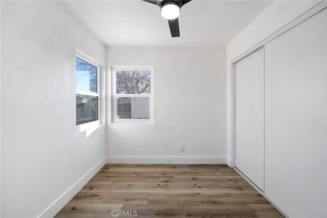 unfurnished bedroom featuring ceiling fan, a closet, and wood-type flooring