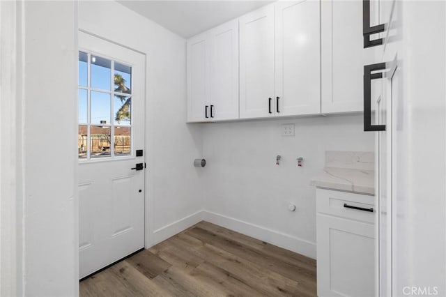 laundry area with washer hookup, light hardwood / wood-style floors, and cabinets